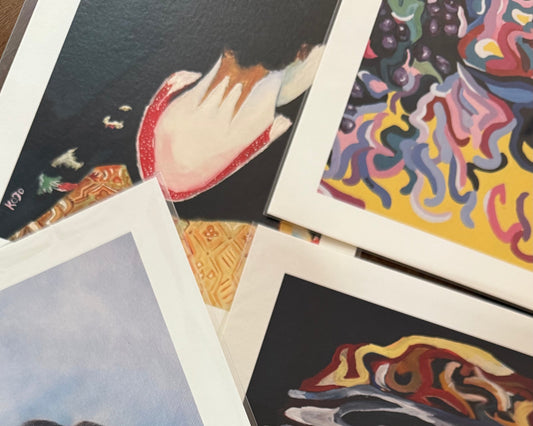 KOJO Art Print Club collectie met verschillende handgesigneerde art prints op premium papier, getoond op een tafel met natuurlijk licht